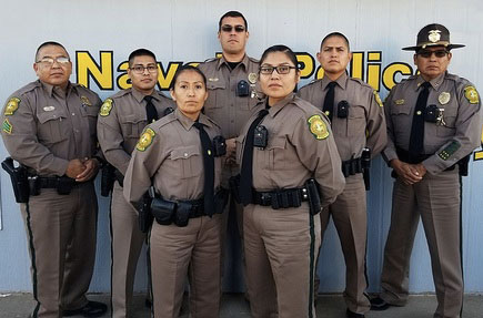 Picture of Navajo Police Officers (Males and Females) standing in front of a wall that says: Navajo Police